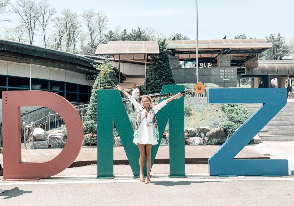 Standing in front of the DMZ sign on the DMZ tour to see North Korea from Seoul, South Korea